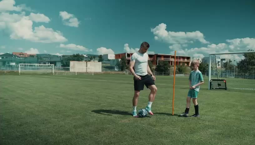 Matúš Marcin ukazuje cvičenie s loptou dvom mladým hráčom na futbalovom ihrisku v Kendiciach.