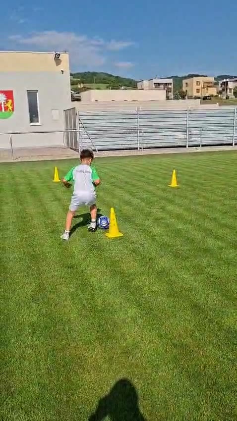 Mladý hráč prechádza slalom s loptou medzi kužeľmi počas individuálneho tréningu.