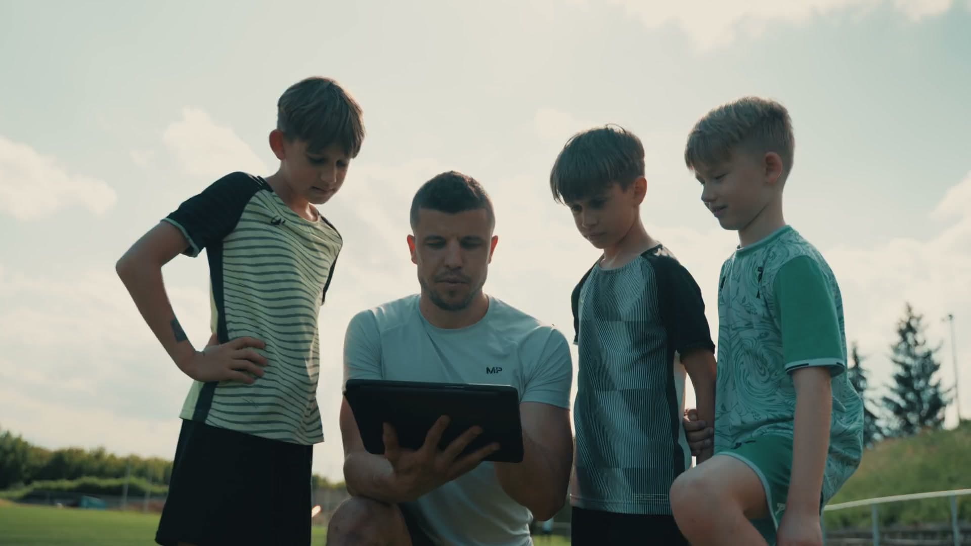 Matúš Marcin ukazuje mladým hráčom spätnú väzbu na tablete počas tréningu.