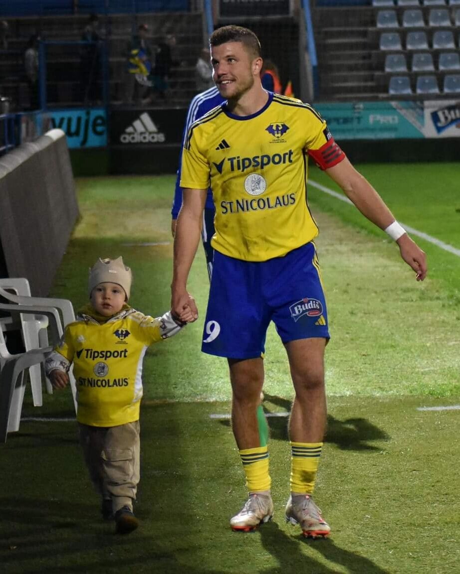 Matúš Marcin drží za ruku mladého fanúšika pri futbalovom ihrisku.